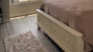 Une chambre à coucher avec un lit, un ventilateur de plafond, une fenêtre donnant sur la plage et une table de chevet avec une lampe.