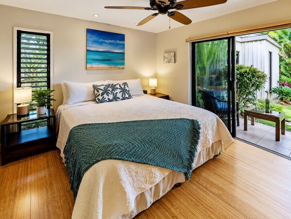 Un dormitorio con cama, ventilador de techo, ventana con persianas, un cuadro y vistas al exterior.