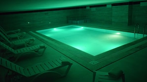 A swimming pool with a tiled deck and lounge chairs. - Grand Rimedya Hotel Bursa (Bursa)