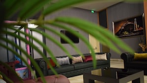 A modern living room with a dark-colored sofa, a black coffee table, and a painting on the wall. - Grand Rimedya Hotel Bursa (Bursa)