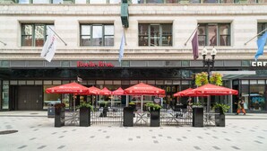 Un bâtiment portant l’enseigne « Roche Bros. », avec des tables à l’extérieur sous des parasols rouges et une enseigne « CAFÉ ».