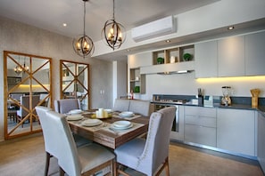 A modern dining area with a wooden table set for four, surrounded by upholstered chairs.