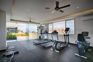 Un gimnasio con cintas de correr, elípticas y equipo de pesas.