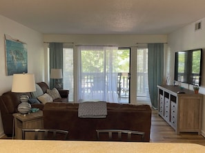 Relax in this stylish living room with a sofa, coffee table, and side table, featuring a mounted TV and sliding glass door to an outdoor patio.