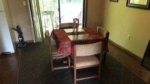 Een eetruimte met een tafel, afgedekt met een rode tafelkleed met bloemenprint, omringd door houten stoelen.