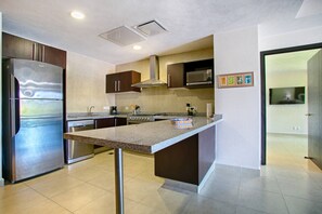 A modern kitchen with stainless steel appliances, a granite countertop, and a microwave. - Beachfront 2BR | Accessible, Pool & Hot Tub (Puerto Vallarta)