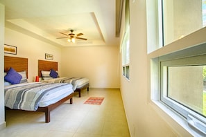 A bedroom with two beds, a ceiling fan, and a window.