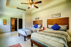 A hotel room with two beds, a ceiling fan, a large window, and a door leading to a bathroom. - Beachfront 2BR | Accessible, Pool & Hot Tub (Puerto Vallarta)