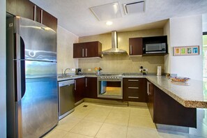 Uma cozinha moderna com eletrodomésticos de aço inoxidável, armários escuros e bancada de granito.