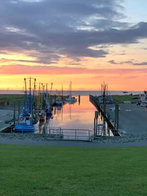 A marina with boats docked, calm water, and a sunset in the background.