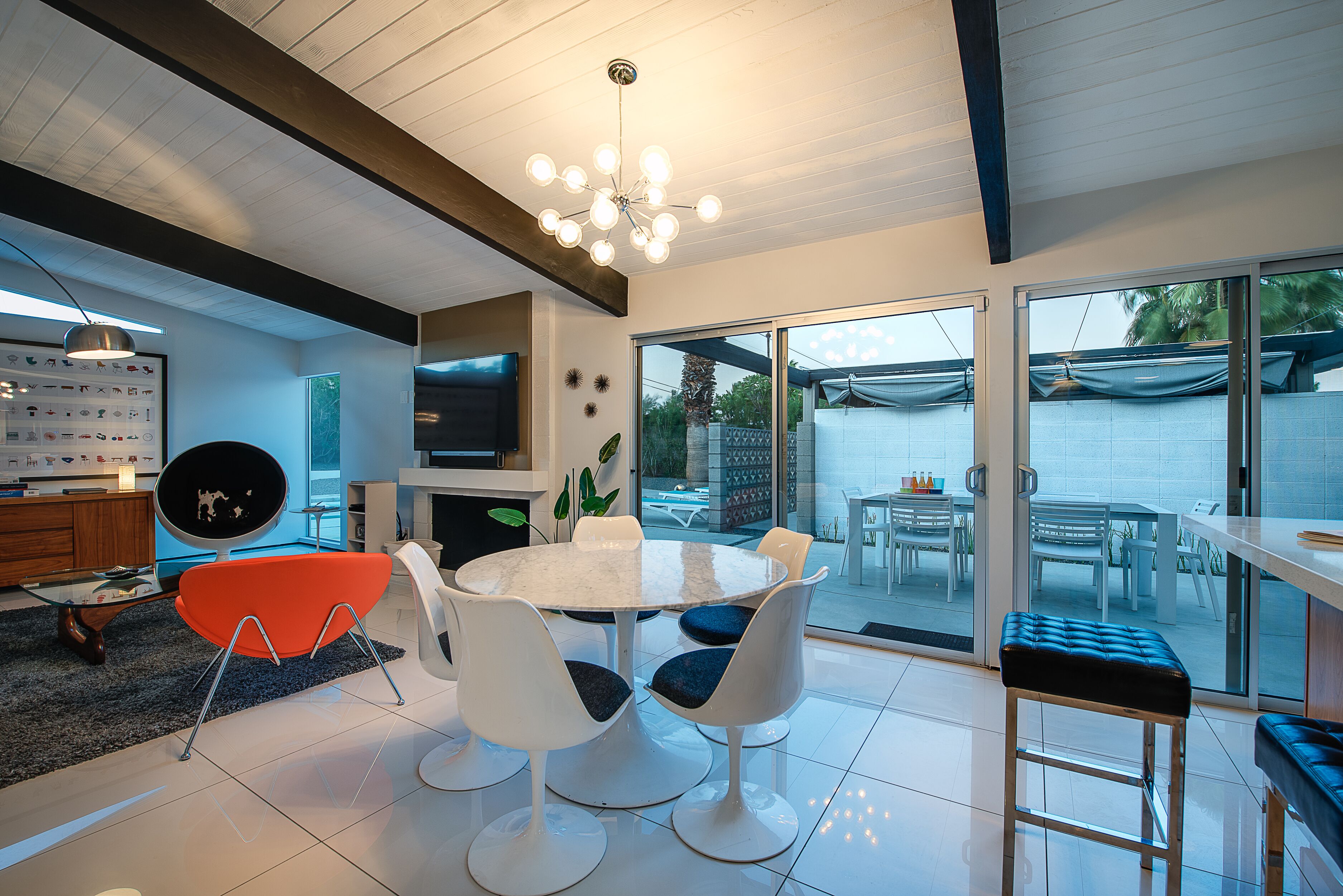 A modern kitchen with white cabinets, a large island, and a dining area with a round table and chairs.