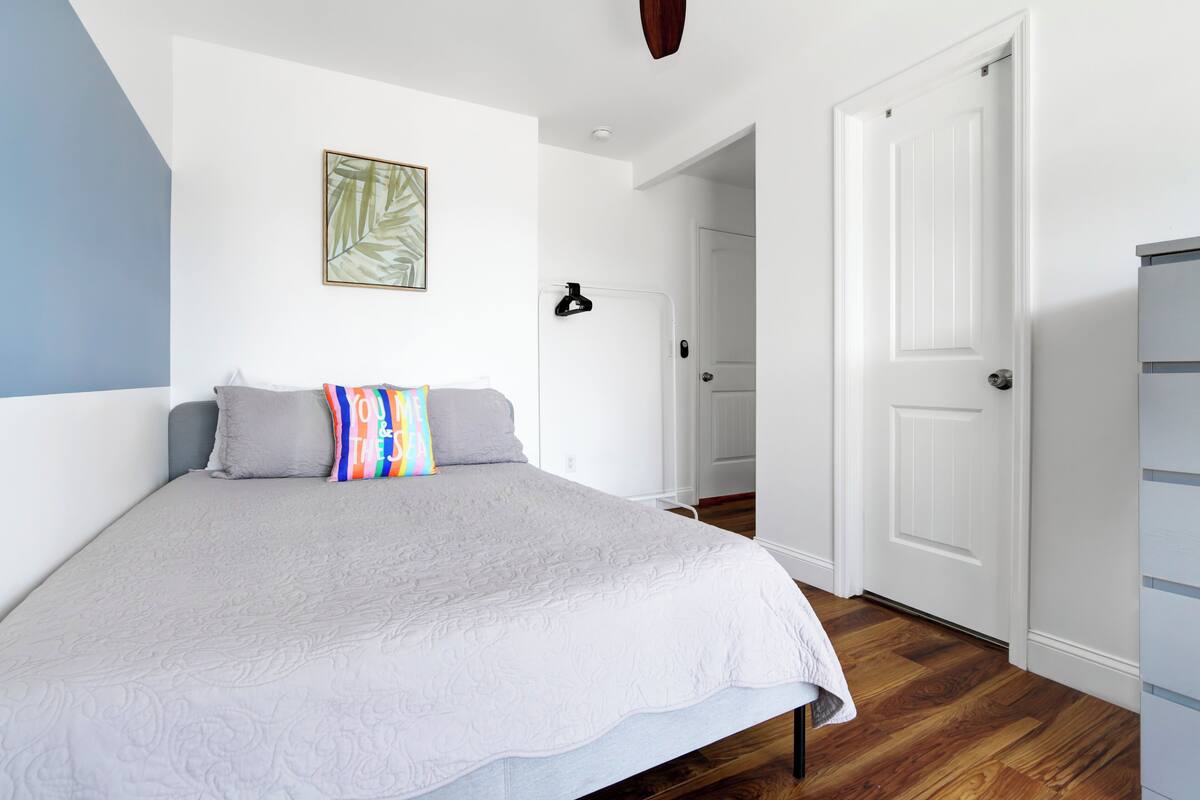 A bedroom with a bed, a door, and a hallway.