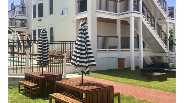 A multi-story building with balconies, outdoor seating, and a pool.