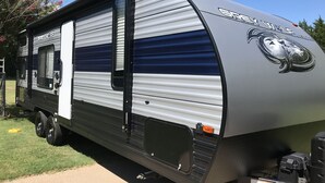 Una caravana gris y azul con un logotipo de 'Grey Wolves', una puerta corredera y un exterior negro.