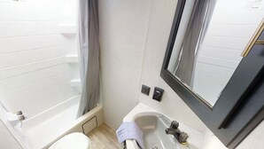 Un baño pequeño con bañera, inodoro, lavamanos y espejo.