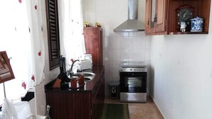 Une cuisine de taille réduite, équipée d’une cuisinière, d’un évier et de meubles de rangement en bois.