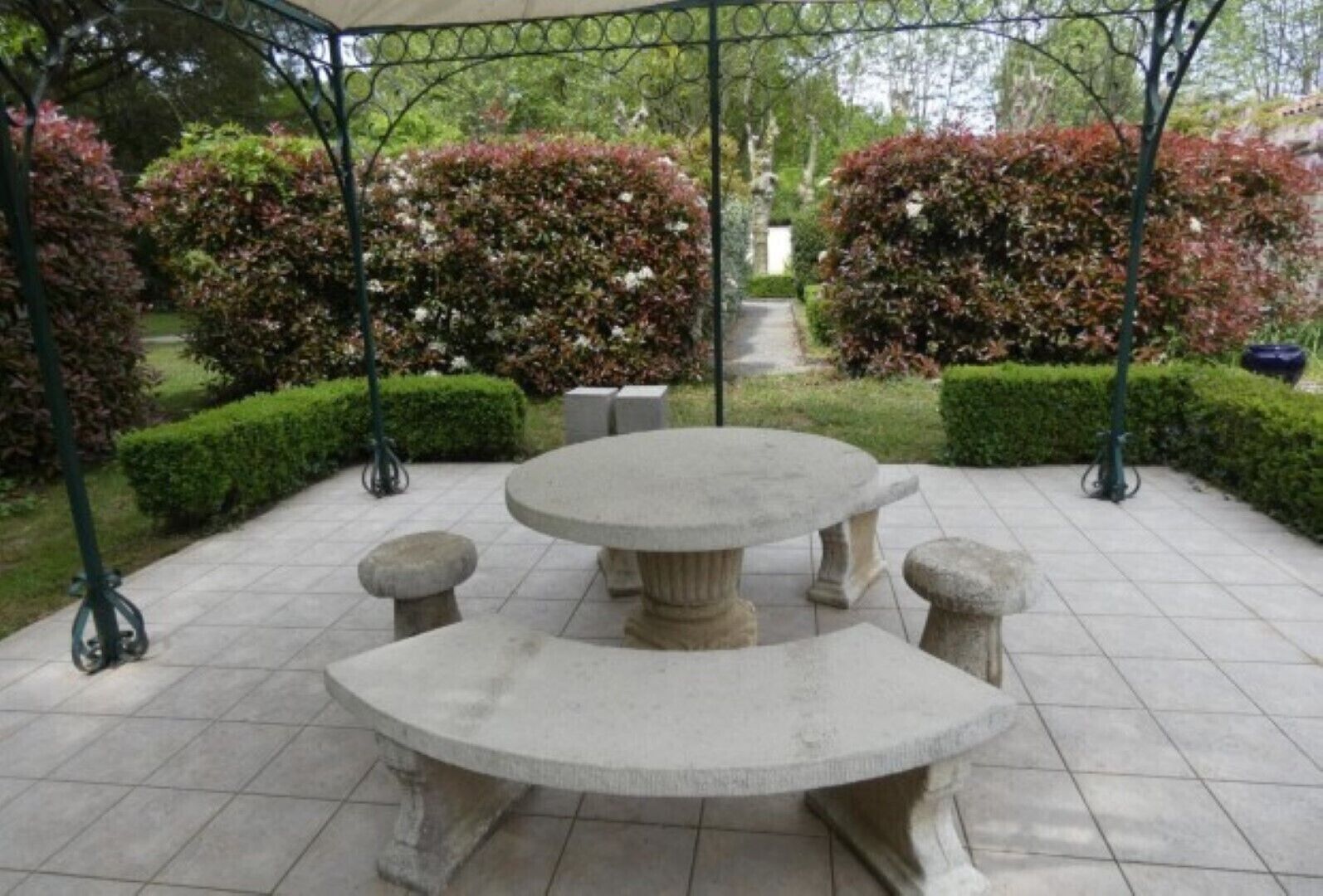 A stone table with four benches in a garden setting.