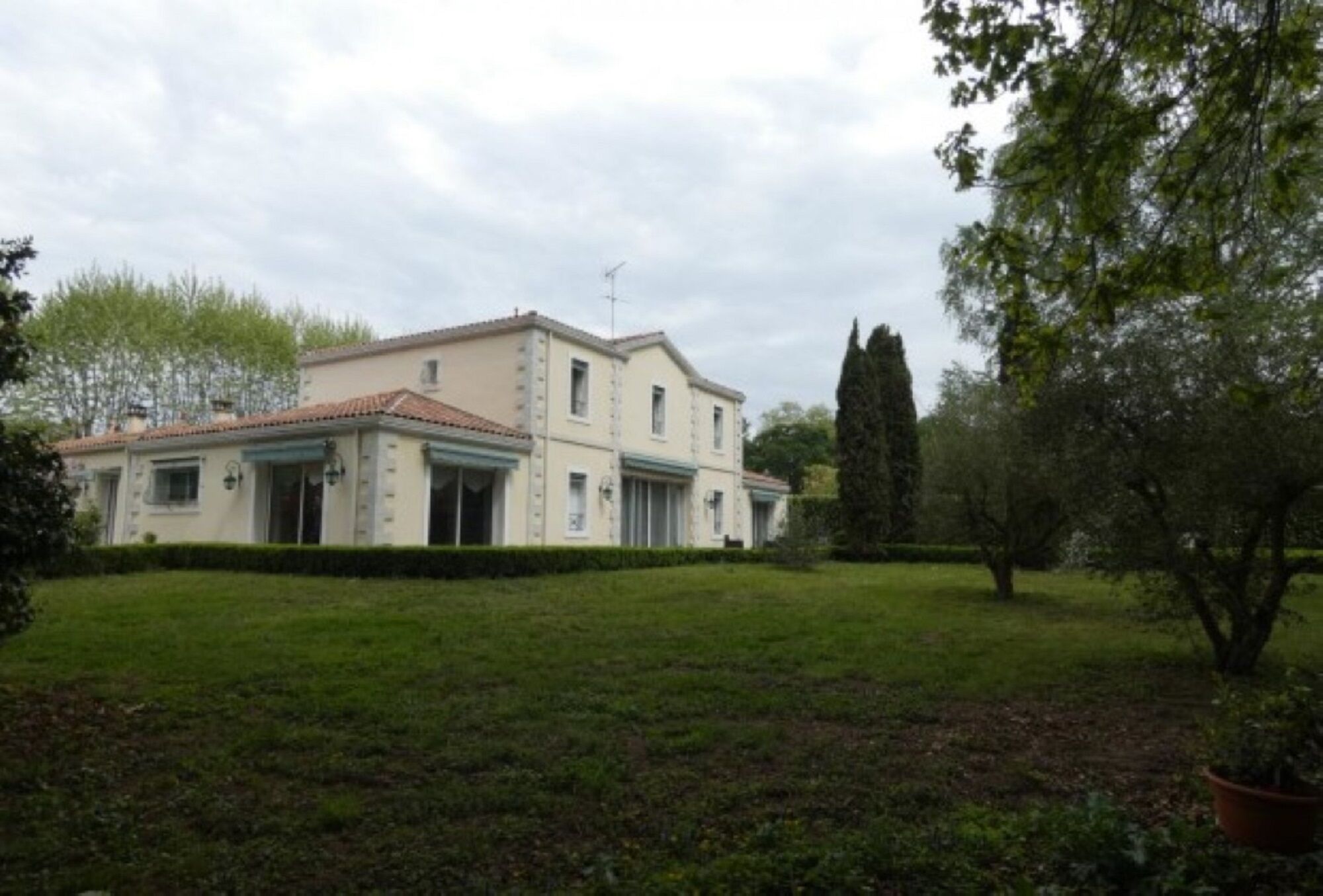 A two-story building with a flat roof and a symmetrical facade, surrounded by a well-maintained lawn and trees.