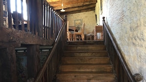 A wooden staircase with a railing, leading to a room with wicker furniture and a painting on the wall.