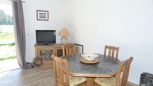 A dining area with a round table, four wooden chairs, a television, a lamp, and a small cabinet. - HOUSE BETWEEN COUNTRYSIDE AND SEA (Saint-Julien-en-Born)