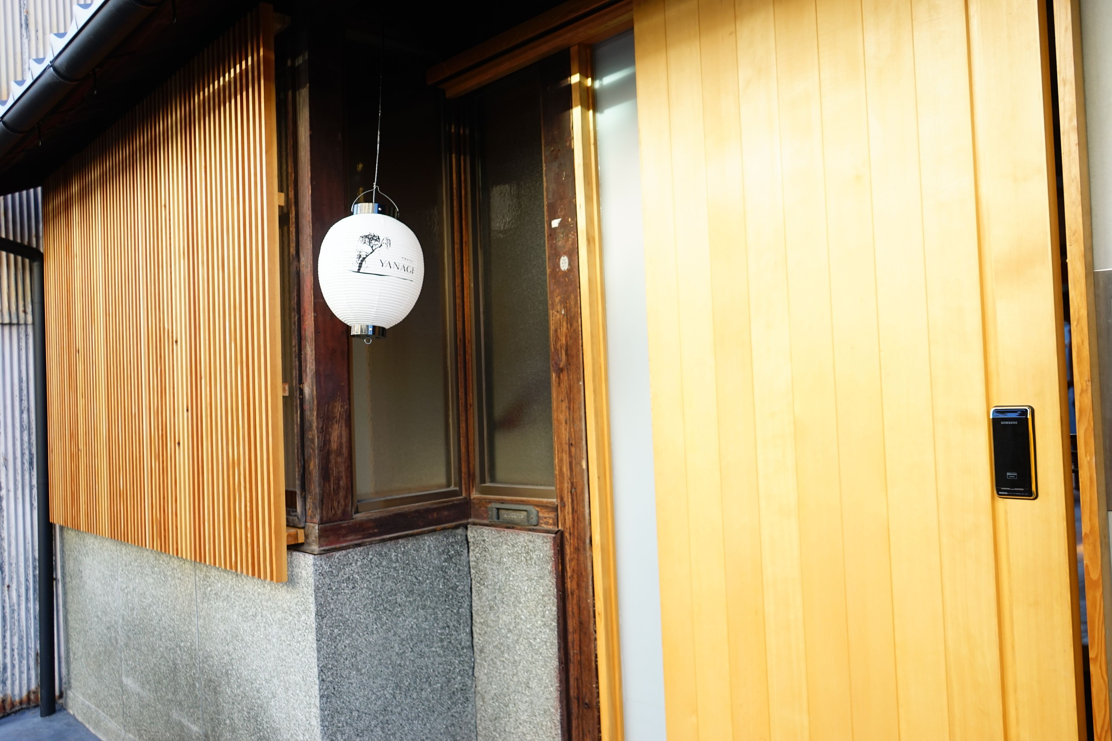 A traditional wooden building with a sliding door and a hanging paper lantern.
