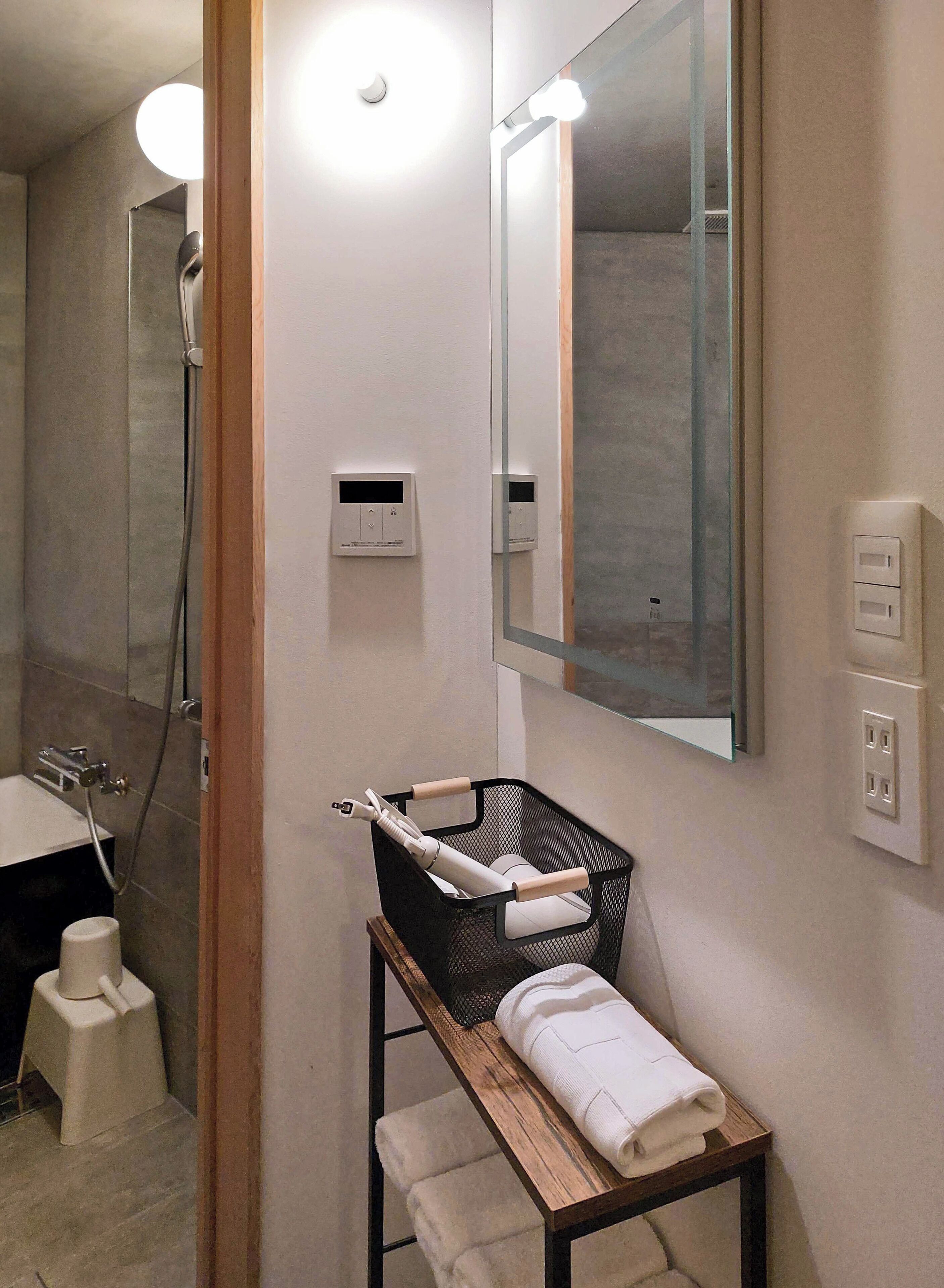 A bathroom with a sink, mirror, towel rack, and a shower.