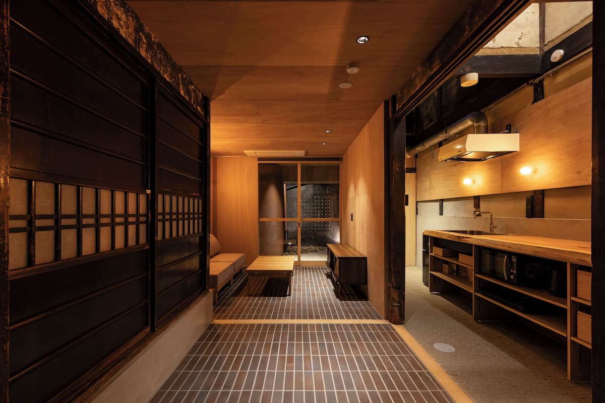 Un couloir étroit avec un plancher en bois, un banc et un coin lavabo avec des étagères.