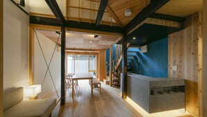 Une pièce spacieuse avec un plancher en bois, un canapé, une table à manger et un coin cuisine doté d’un comptoir.