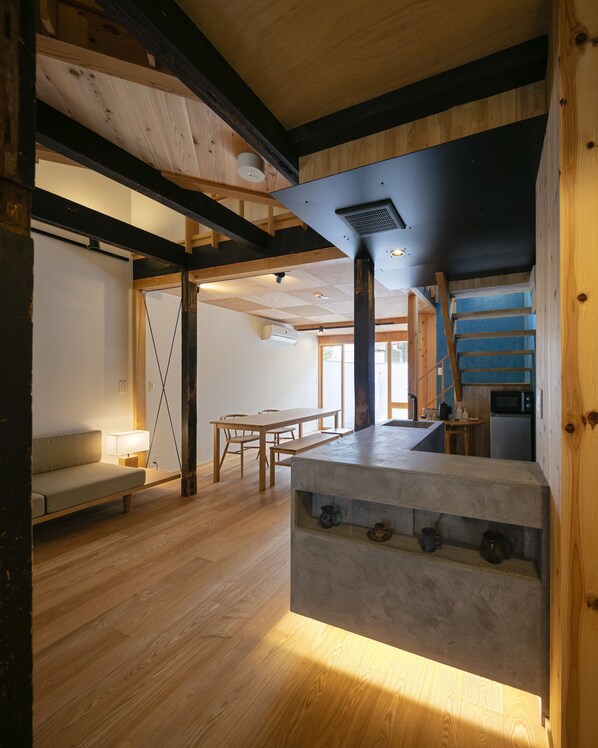 A spacious room with wooden floors, a dining area, and a kitchen area.