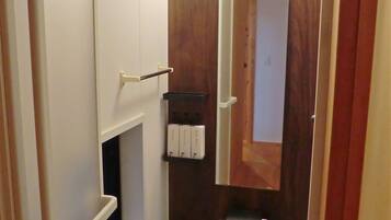 Un baño pequeño con tocador de madera, inodoro blanco y una pequeña repisa con artículos de aseo.