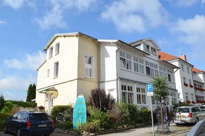 Un bâtiment à deux étages, doté d’une façade blanche et d’un toit recouvert de tuiles rouges.