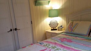 Een slaapkamer met een bed, nachtkastje, lamp en kledingkast.