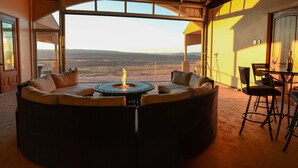 Une pièce dotée d’une grande fenêtre, d’une table ronde avec un foyer et d’un coin bar.