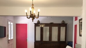 A living room with a white sofa, a wooden cabinet, a chandelier, and a red door. - St RAPHAEL 400m from the beach 2 bedrooms sleeps 6 (Saint-Raphaël)