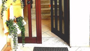 A hotel entrance with a wooden door, a staircase, and a guest review sign.
