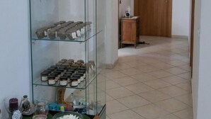 A hallway with a glass display case containing jars, a wooden door, and a tiled floor.