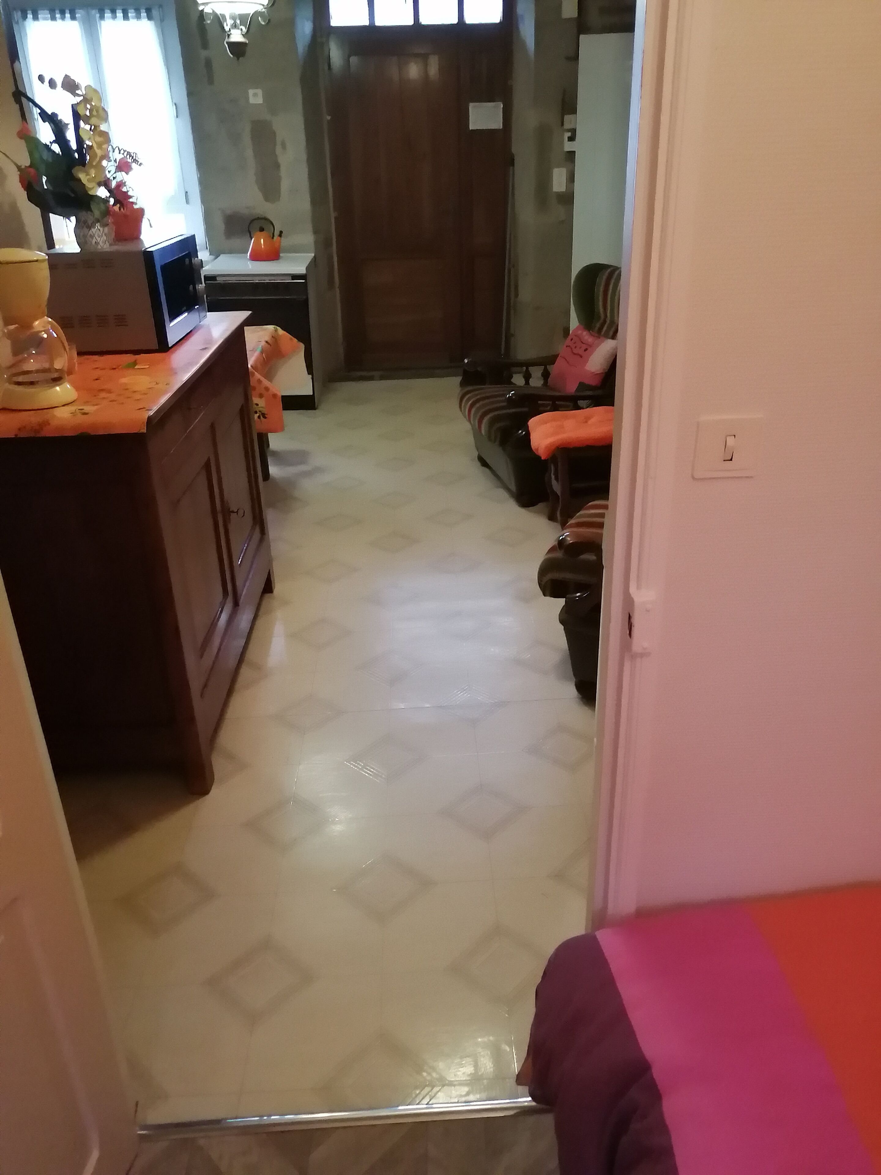 A hallway with a wooden cabinet, a sofa, and a door leading to another room.