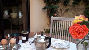 Une table dressée avec des assiettes, des bols, une théière et un vase contenant une rose.