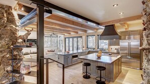 A modern kitchen with a large island, stone walls, and a rustic deer sculpture. - Experience luxury in this 4-bedroom, 3.5-bath home in Breckenridge at Arrow Darrow! (Breckenridge)