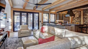 A spacious living area with a leather sofa, a dining table, and a kitchen in the background. - Experience luxury in this 4-bedroom, 3.5-bath home in Breckenridge at Arrow Darrow! (Breckenridge)