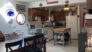 A spacious kitchen with wooden cabinets, a dining area with a table and chairs, and a staircase leading to an upper level. - Saint Leonard Long Beach Beach House (St Leonard)
