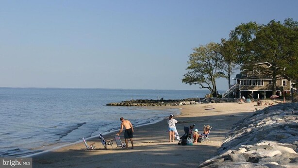 A beach with a house in the background, a rocky shoreline, and people near the water. - Saint Leonard Long Beach Beach House (St Leonard)