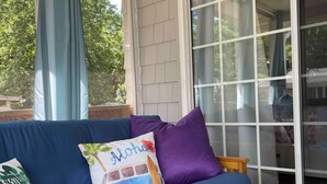 A blue sofa with colorful pillows, a woven mat, and a bowl of lemons on a table. - Saint Leonard Long Beach Beach House (St Leonard)
