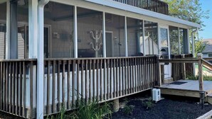 A two-story house with a covered porch and a fenced deck area. - Saint Leonard Long Beach Beach House (St Leonard)