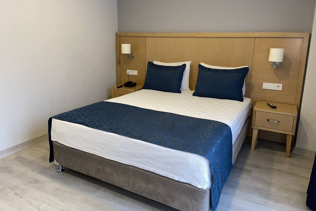 A neatly made bed with a blue and white bedspread, two bedside tables with lamps, and a wooden headboard.