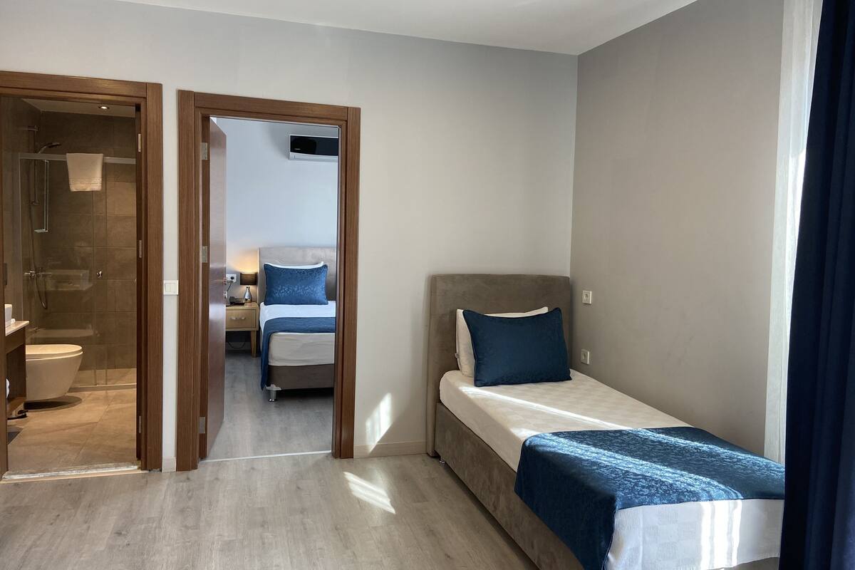 A modern hotel room with a single bed, a bedside table, a nightstand, a shower area, and a toilet.