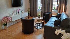 Una sala de estar moderna con un televisor de pantalla plana, un sofá, una mesa de centro y una planta en maceta.