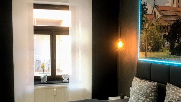 Un dormitorio moderno con una cama grande, vistas al exterior y una lámpara fijada a la pared.