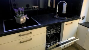 Una cocina moderna con encimera negra, lavavajillas Bosch y un fregadero.