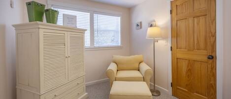 A room with a wardrobe, a sofa, a lamp, and a wooden door.